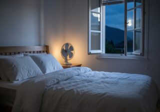 Chambre calme avec draps en lin et ventilateur pour mieux dormir pendant les nuits chaudes d'été